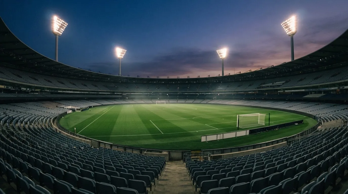 An empty football stadium with floodlight masts at dusk