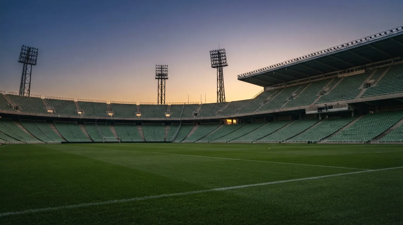 An empty football stadium with floodlight masts at dusk