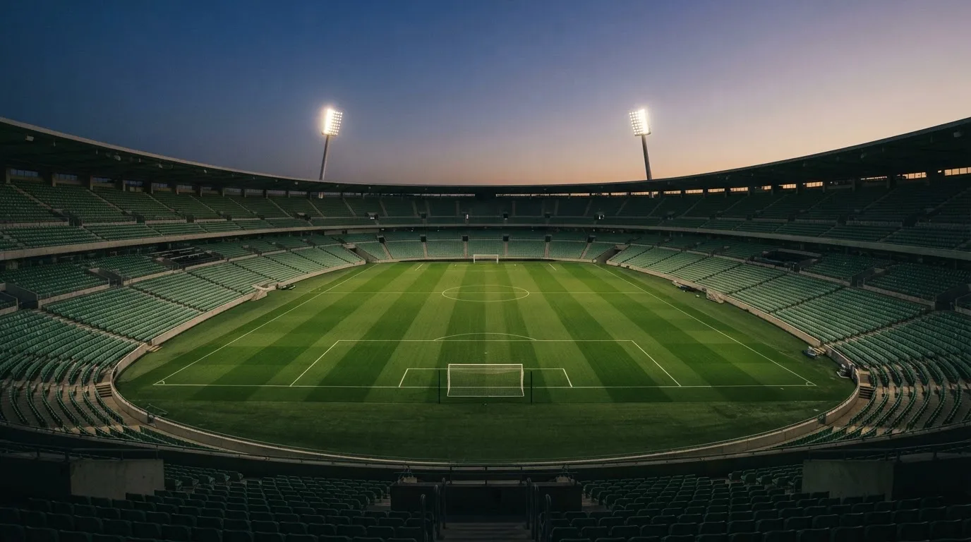 An empty football stadium with floodlight masts at dusk