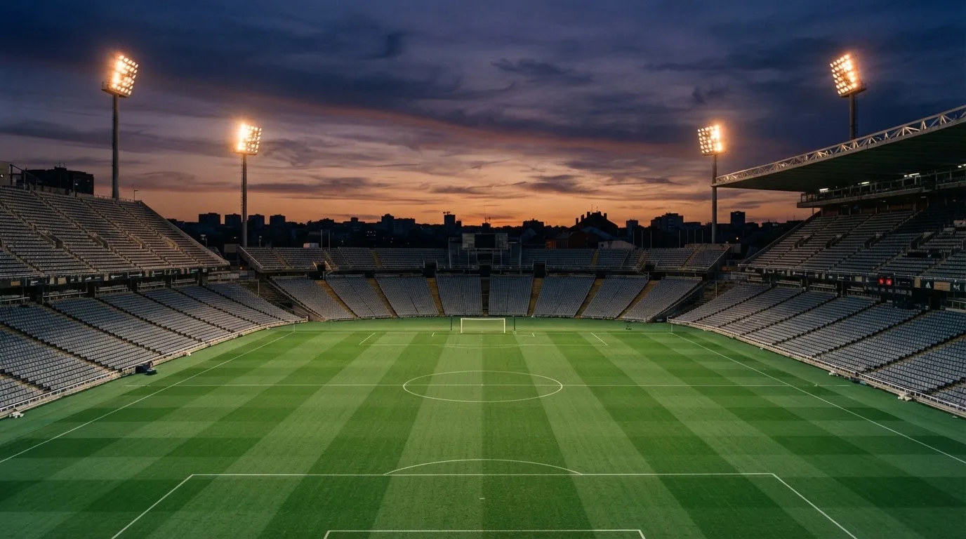 An empty football stadium with floodlight masts at dusk