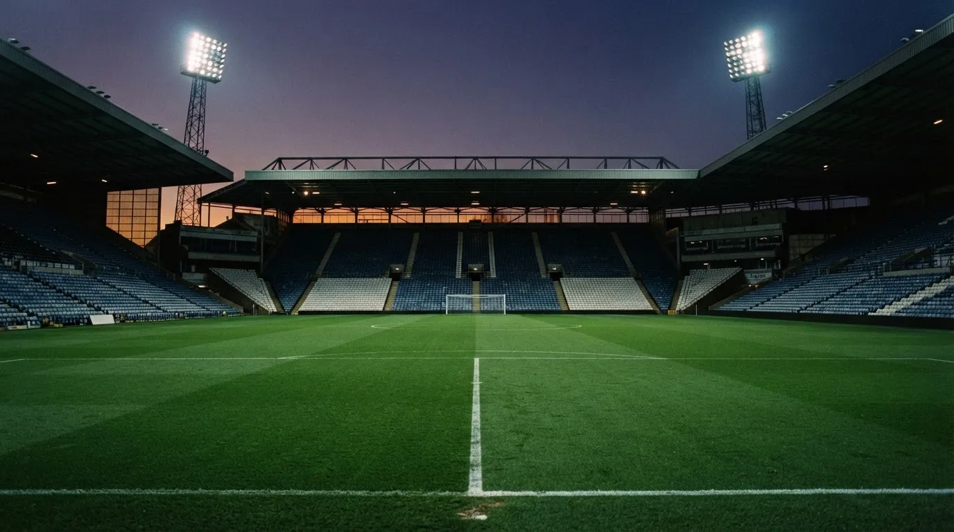 An empty football stadium with floodlight masts at dusk