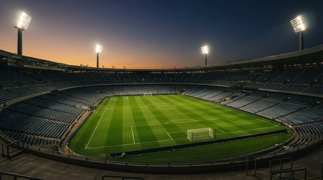An empty football stadium with floodlight masts at dusk