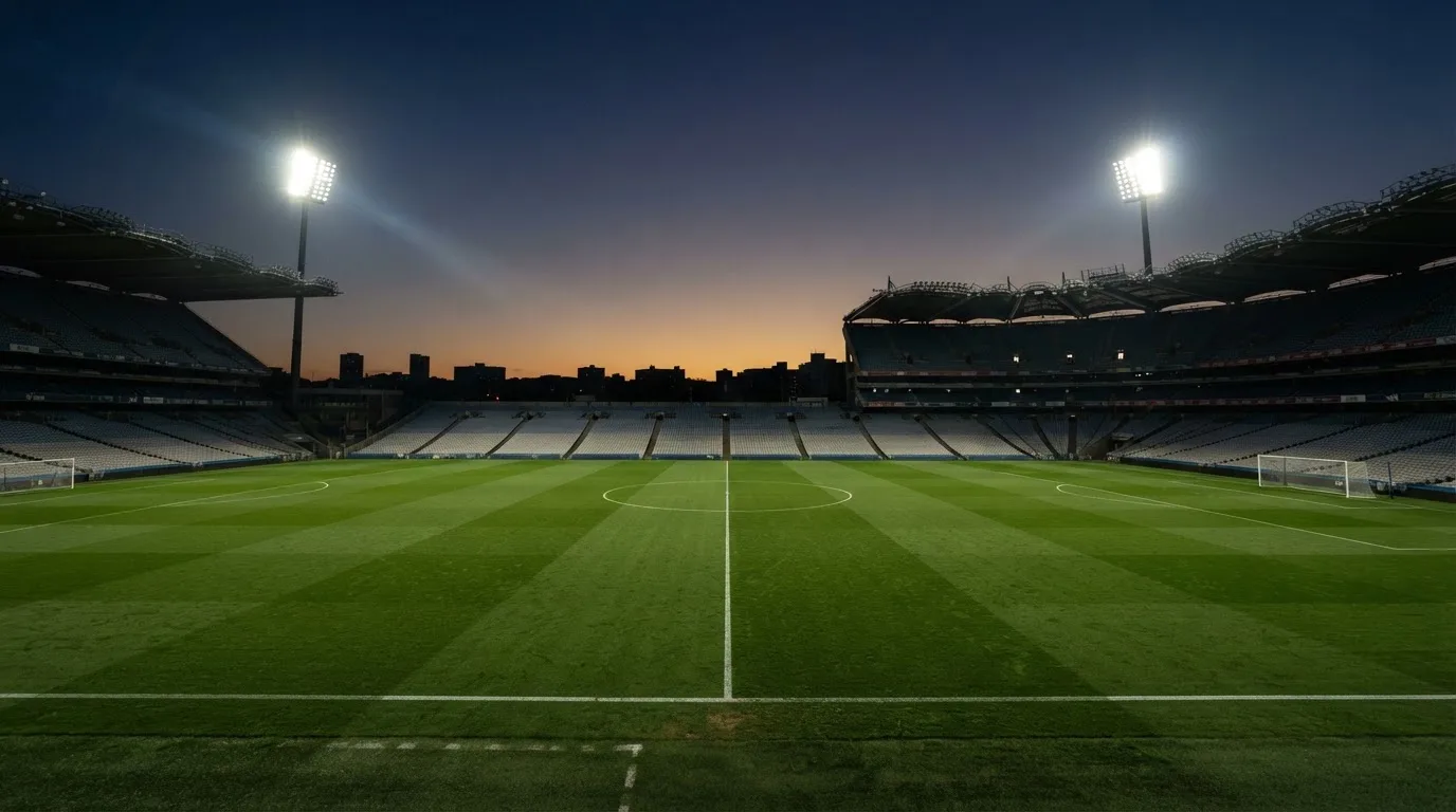 An empty football stadium with floodlight masts at dusk