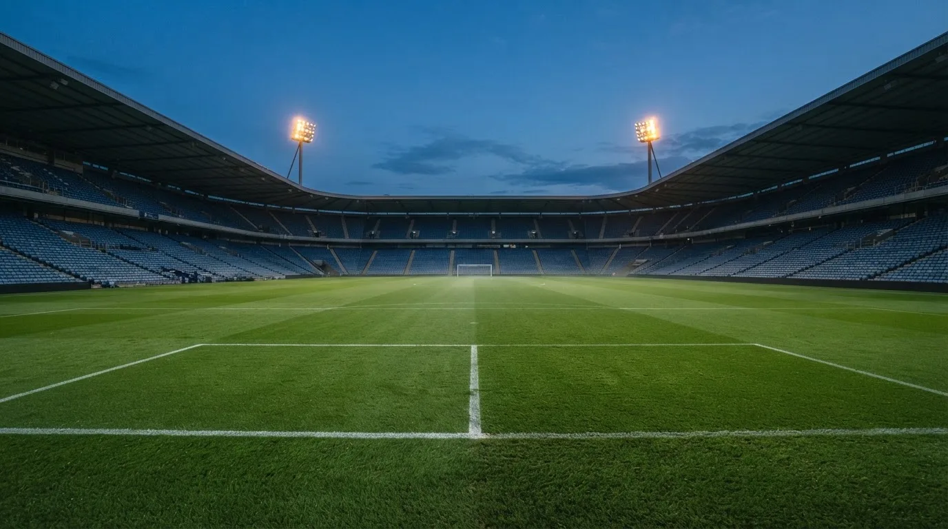 An empty football stadium with floodlight masts at dusk