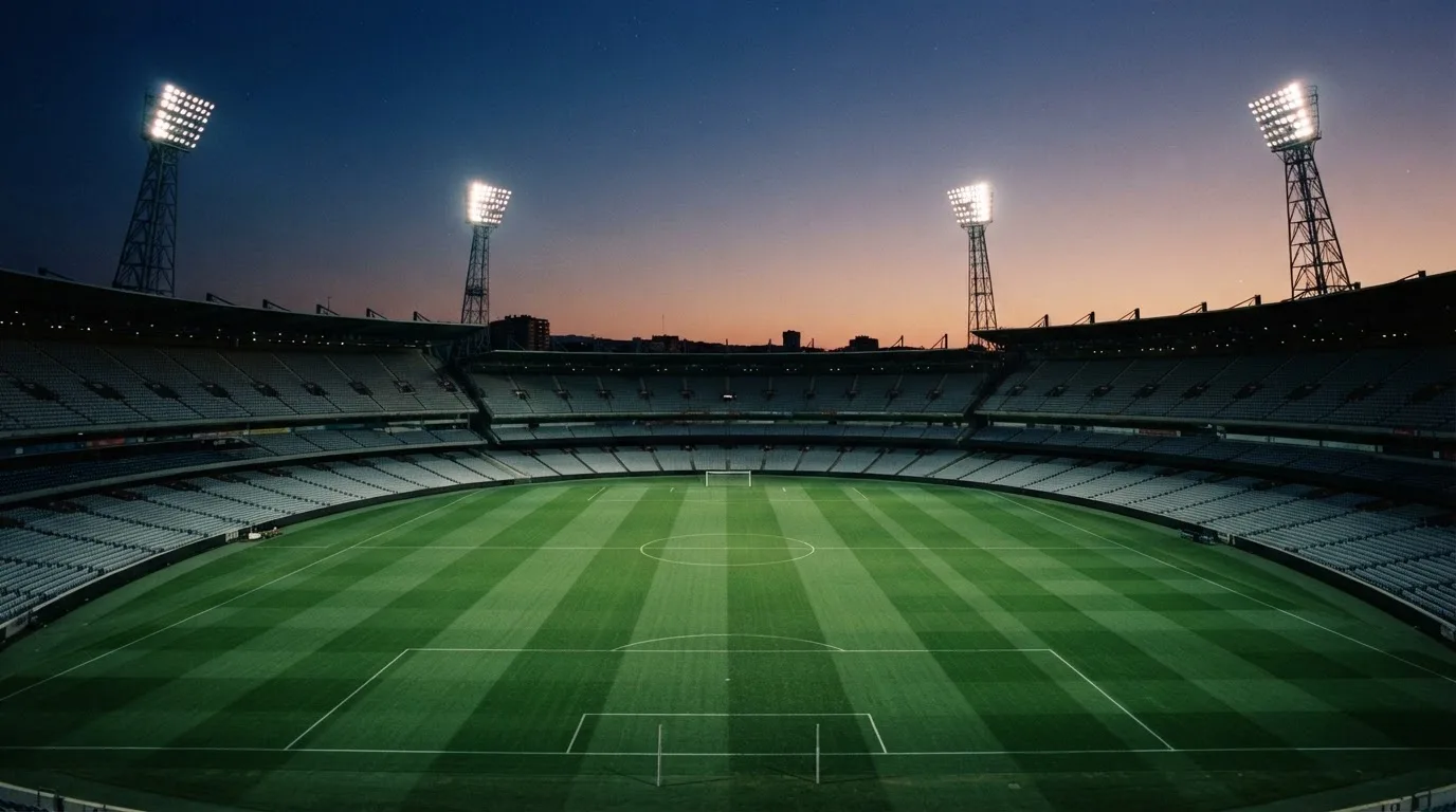 An empty football stadium with floodlight masts at dusk