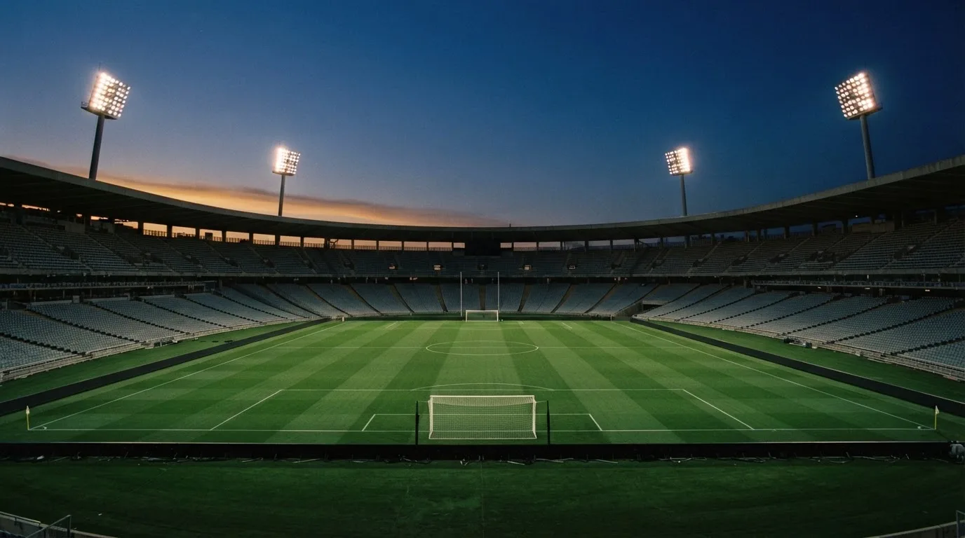 An empty football stadium with floodlight masts at dusk