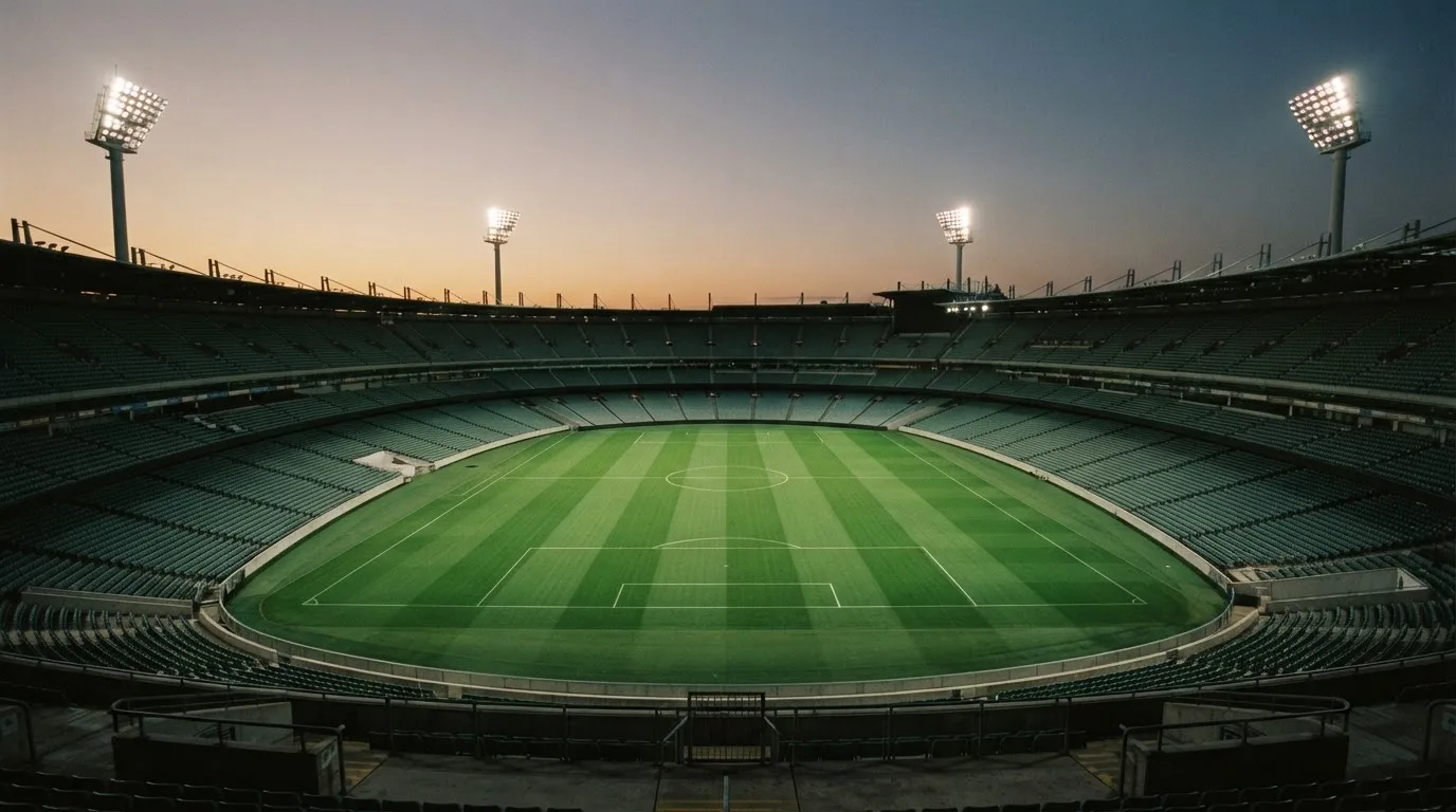 An empty football stadium with floodlight masts at dusk
