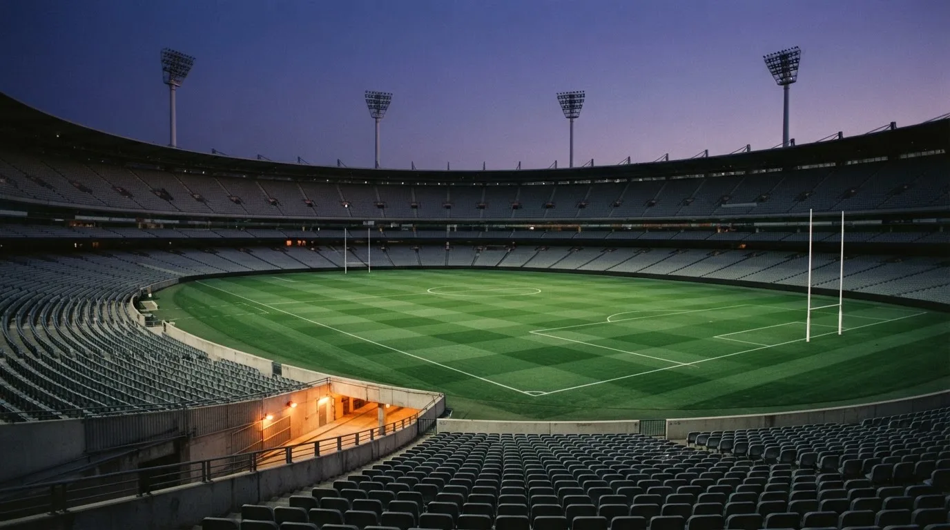 An empty football stadium with floodlight masts at dusk