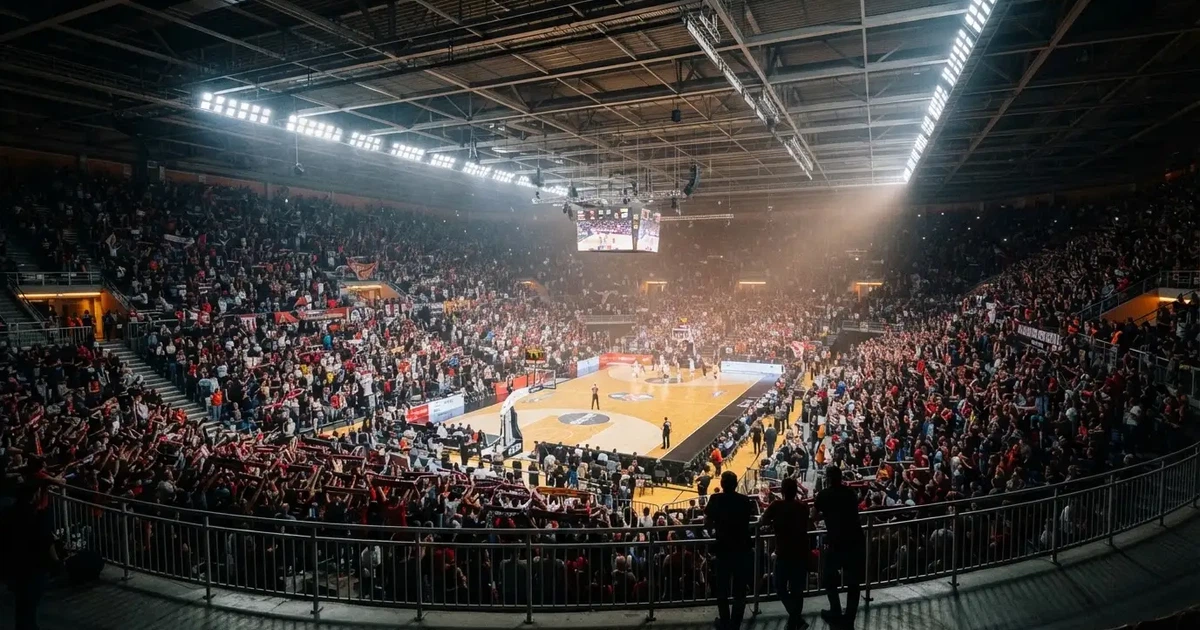 A packed sports hall under floodlights photographed from a long way off