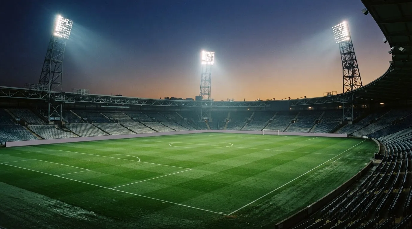 An empty football stadium with floodlight masts at dusk