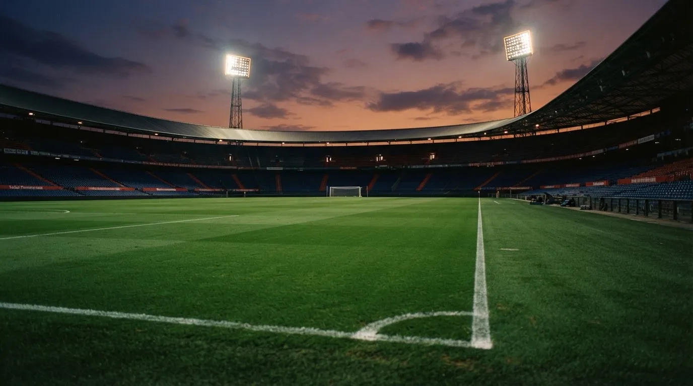 An empty football stadium with floodlight masts at dusk