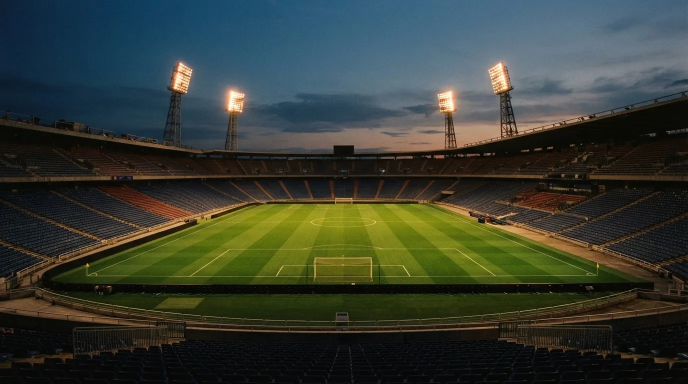 An empty football stadium with floodlight masts at dusk
