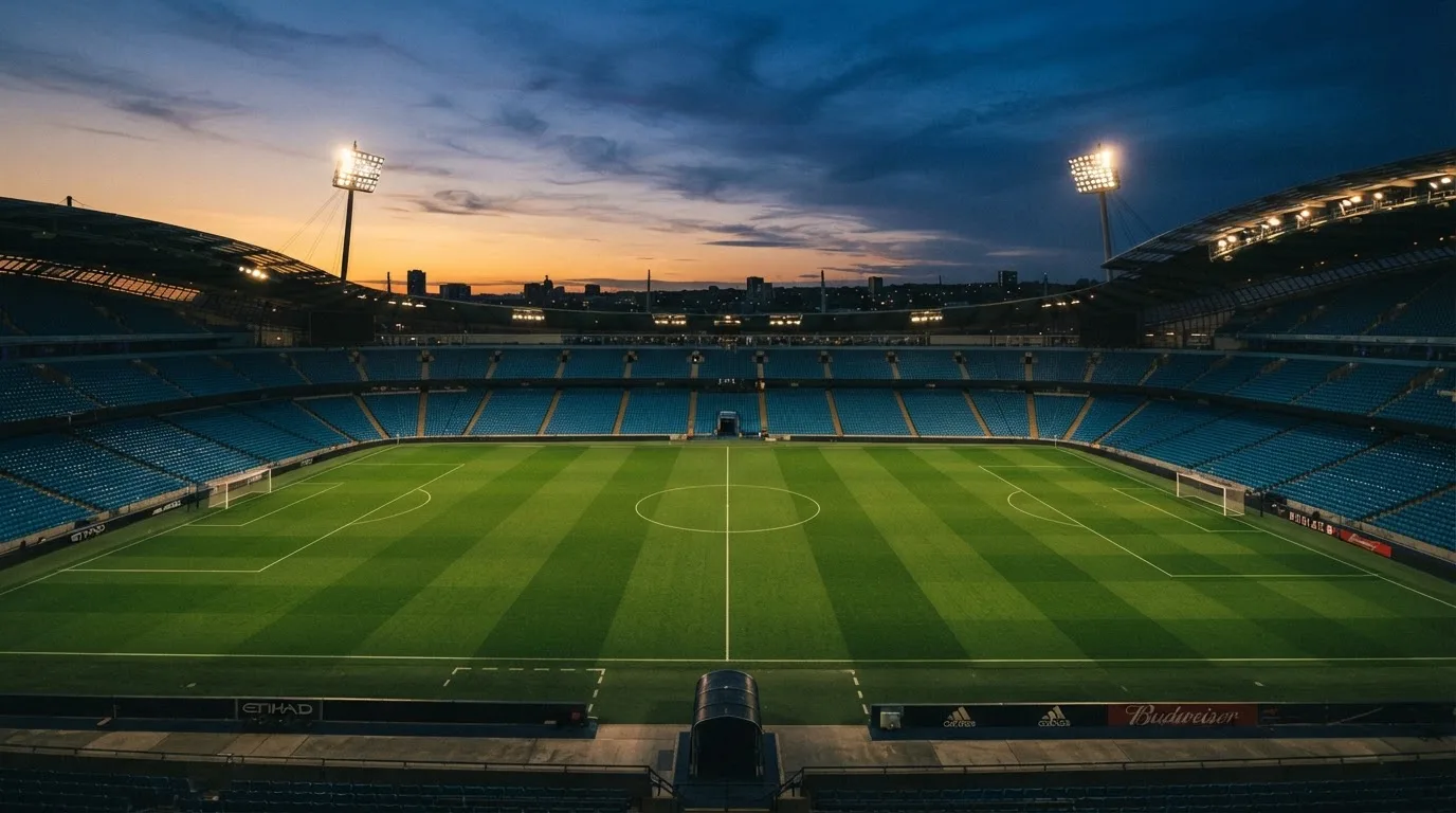 An empty football stadium with floodlight masts at dusk