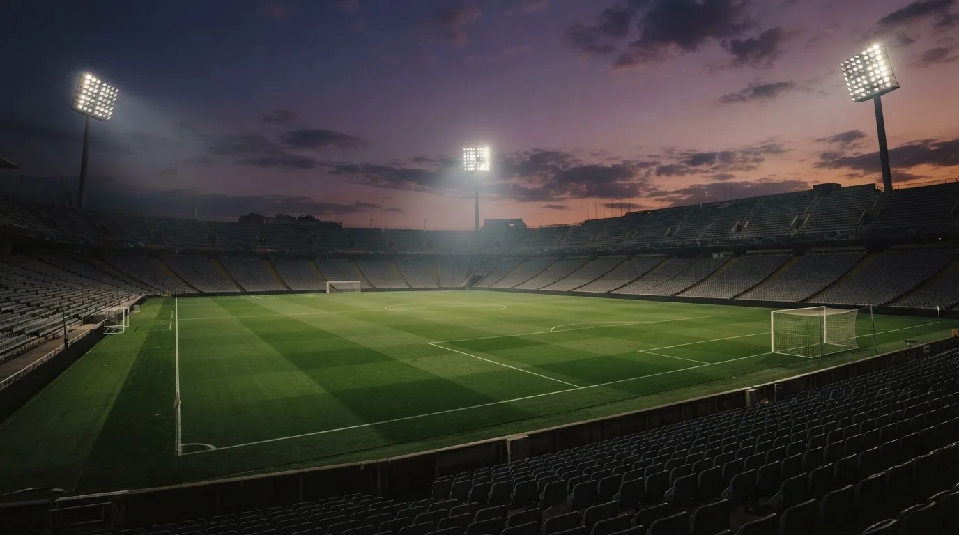 An empty football stadium with floodlight masts at dusk