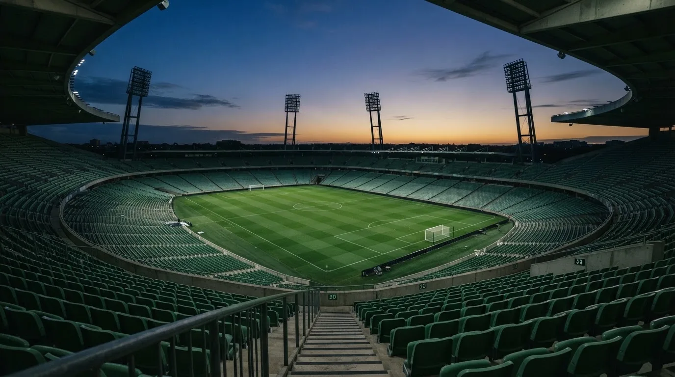 An empty football stadium with floodlight masts at dusk