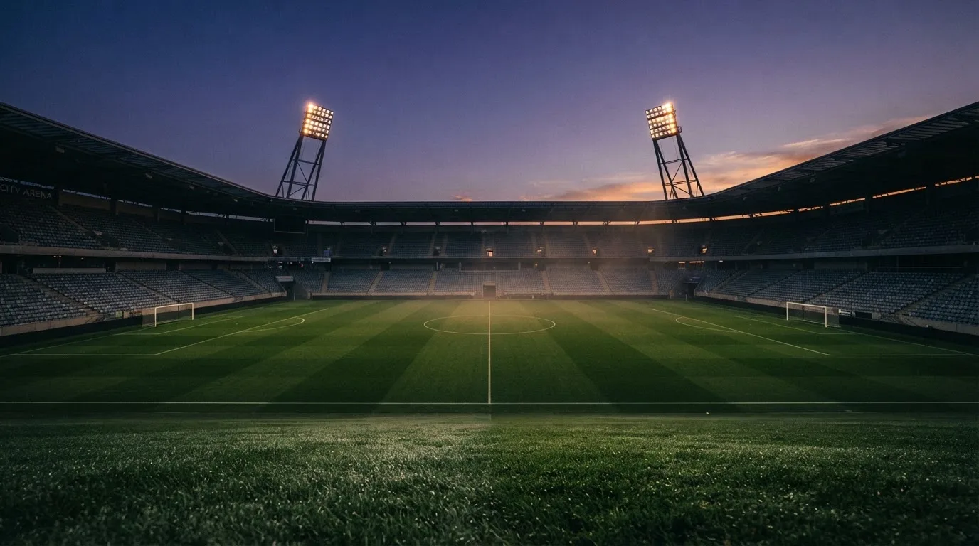 An empty football stadium with floodlight masts at dusk
