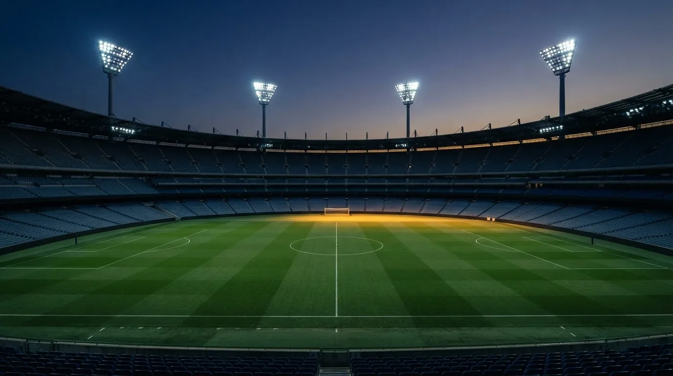 An empty football stadium with floodlight masts at dusk