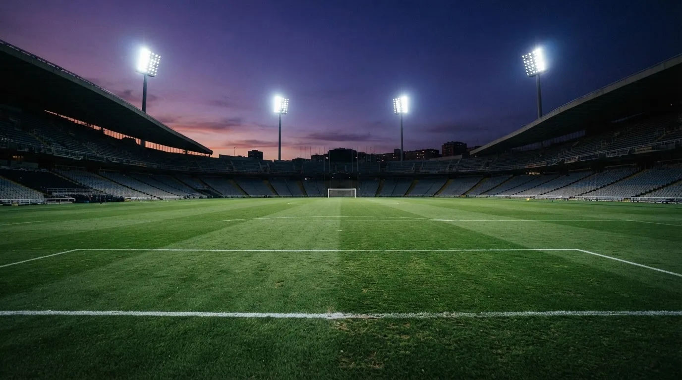 An empty football stadium with floodlight masts at dusk
