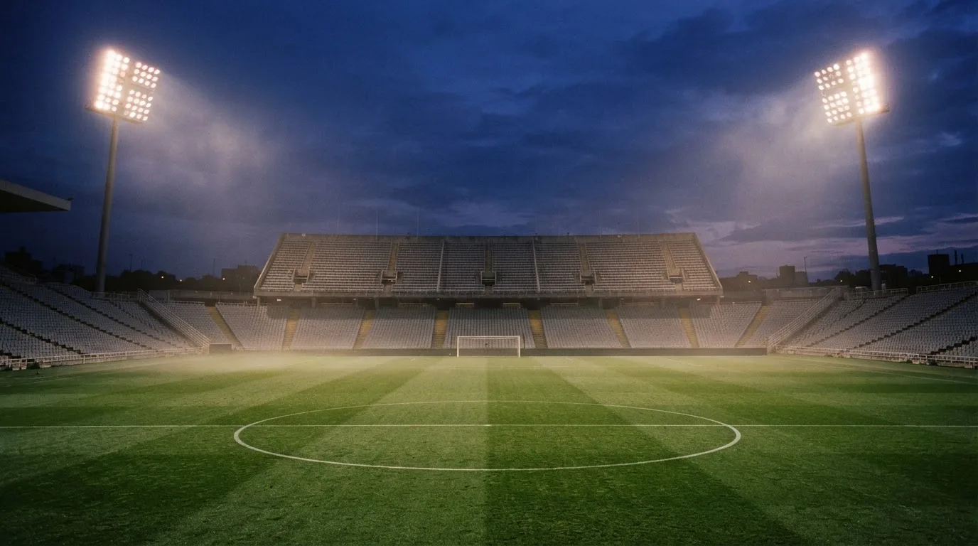 An empty football stadium with floodlight masts at dusk