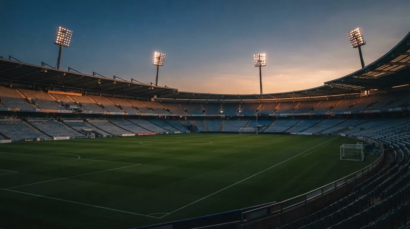 An empty football stadium with floodlight masts at dusk