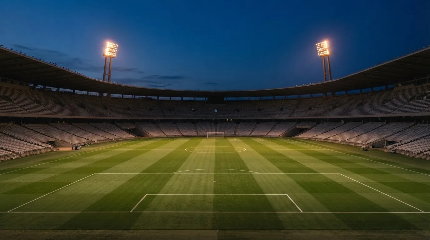 An empty football stadium with floodlight masts at dusk