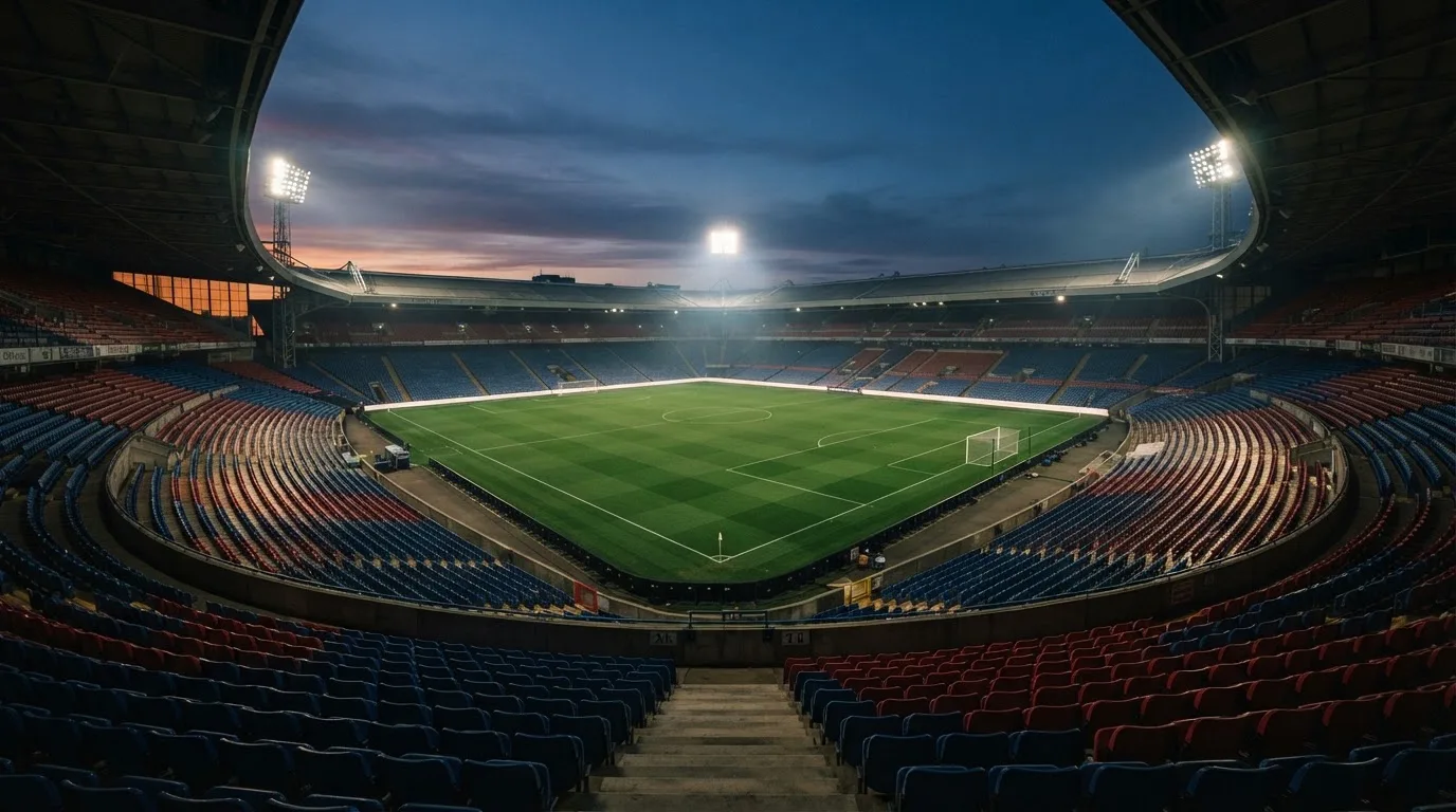 An empty football stadium with floodlight masts at dusk