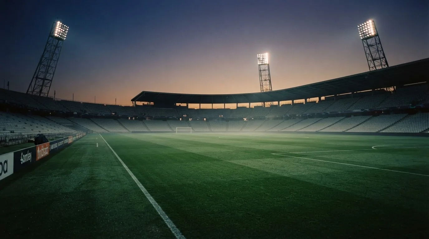 An empty football stadium with floodlight masts at dusk
