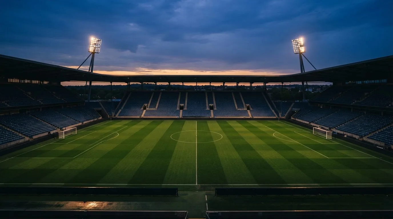 An empty football stadium with floodlight masts at dusk