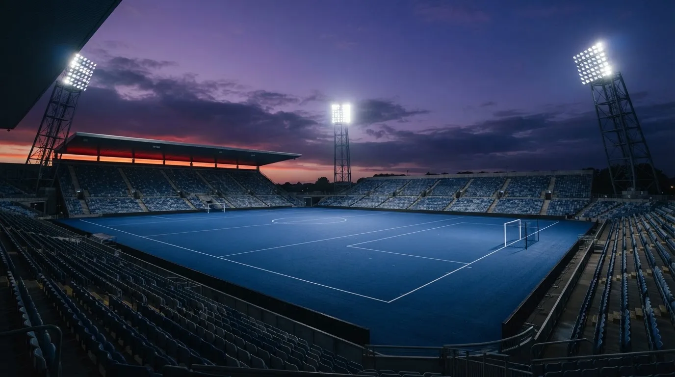 An empty football stadium with floodlight masts at dusk