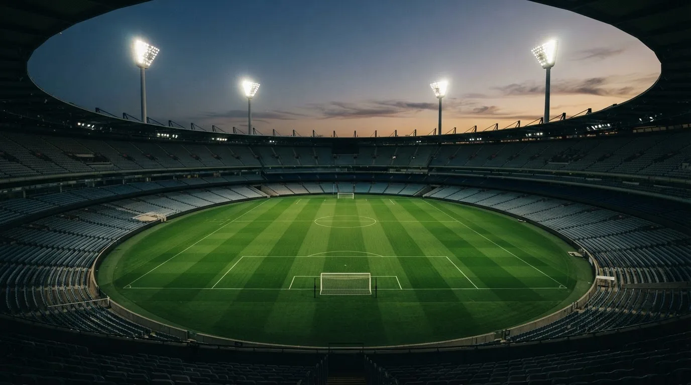 An empty football stadium with floodlight masts at dusk