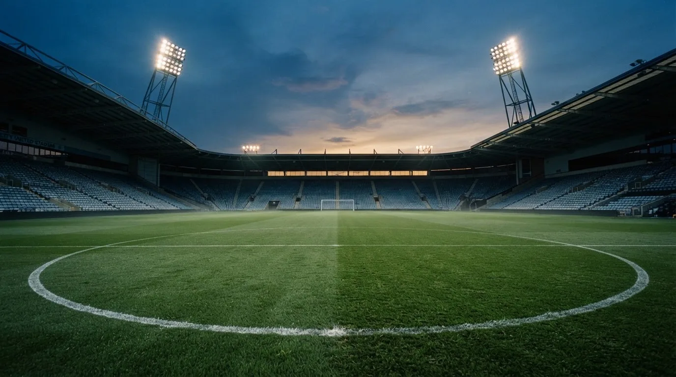 An empty football stadium with floodlight masts at dusk