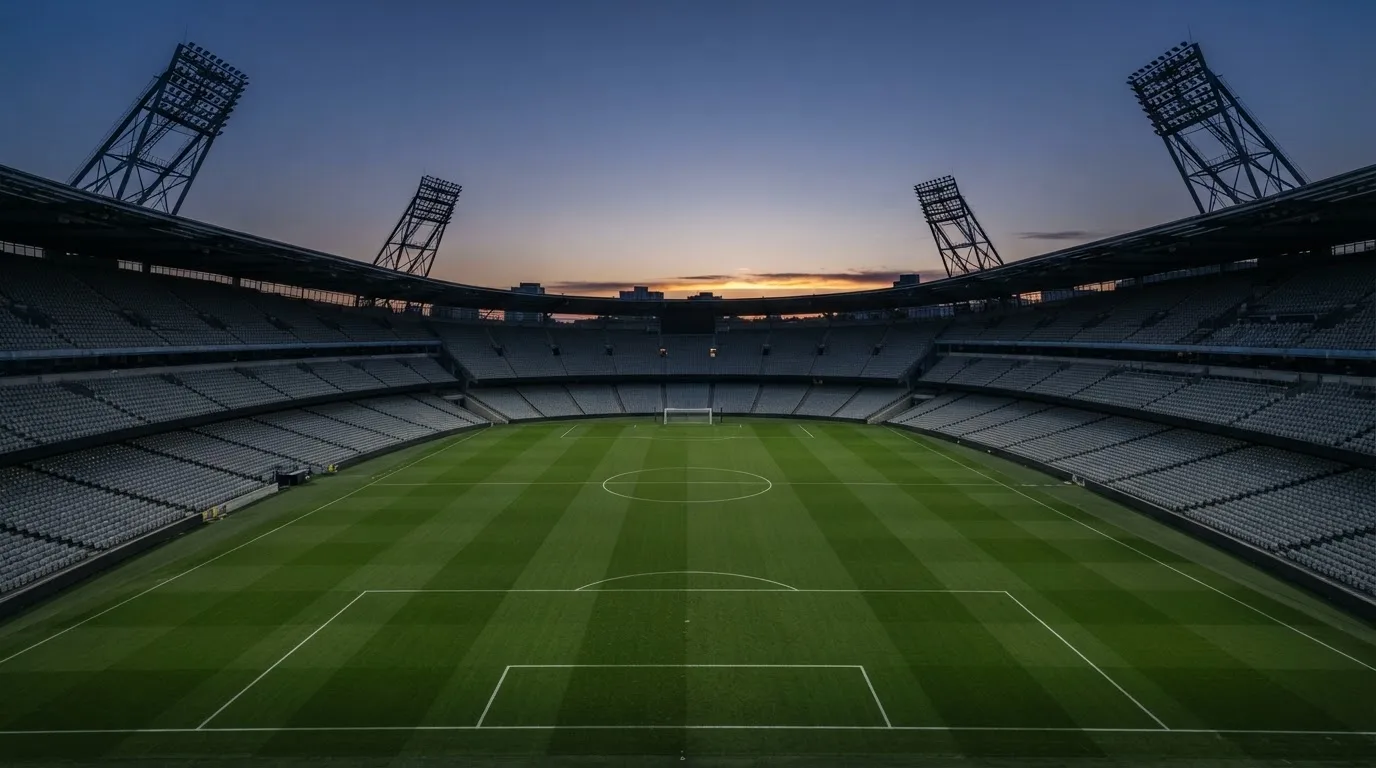 An empty football stadium with floodlight masts at dusk