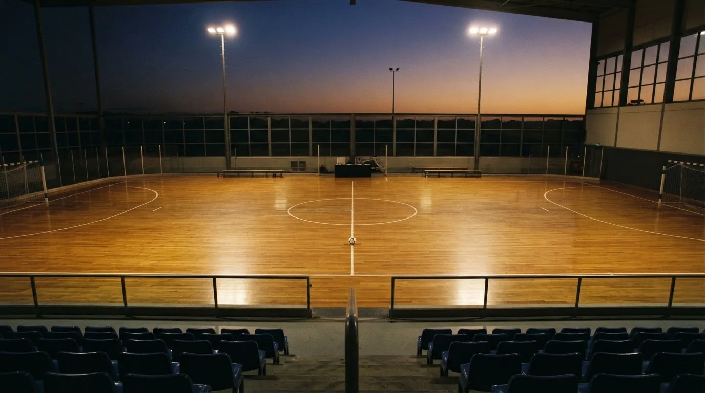 An empty football stadium with floodlight masts at dusk