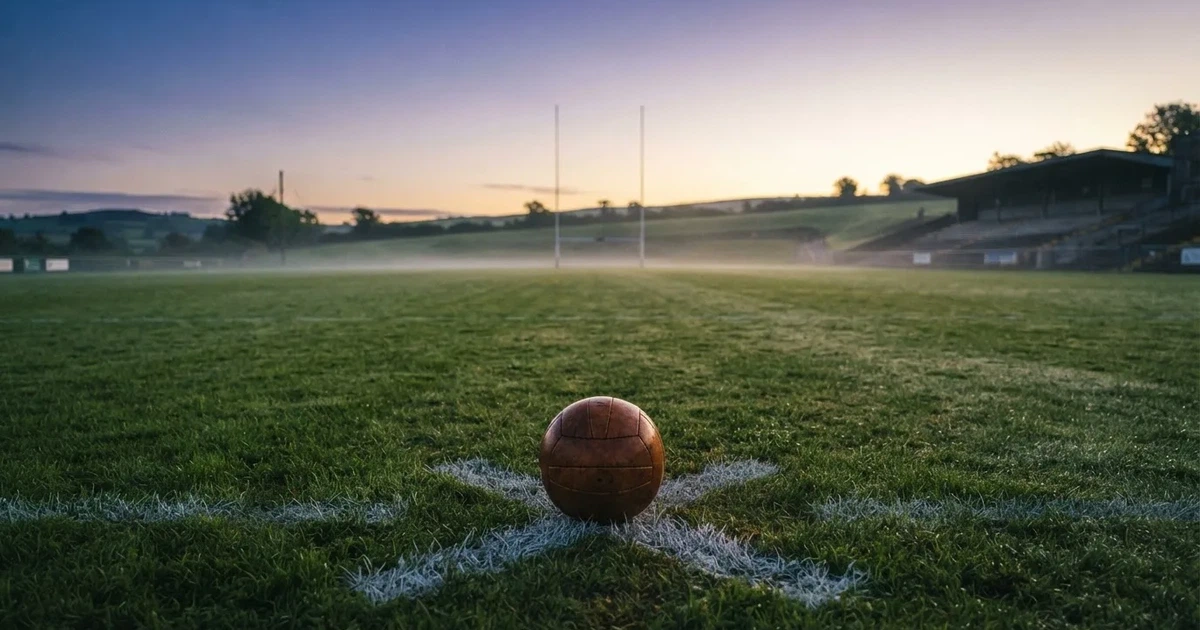 A ball on the centre spot of a grass pitch in morning light