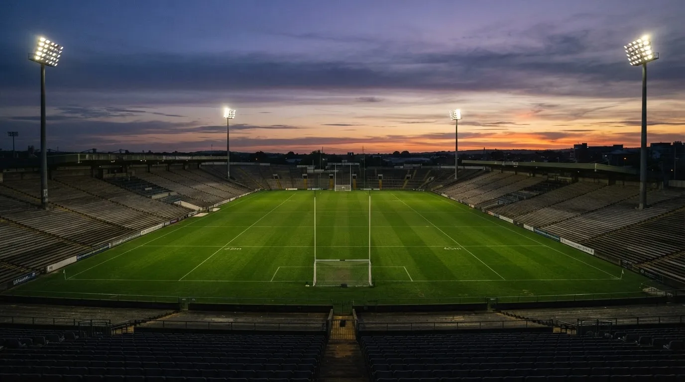 An empty football stadium with floodlight masts at dusk