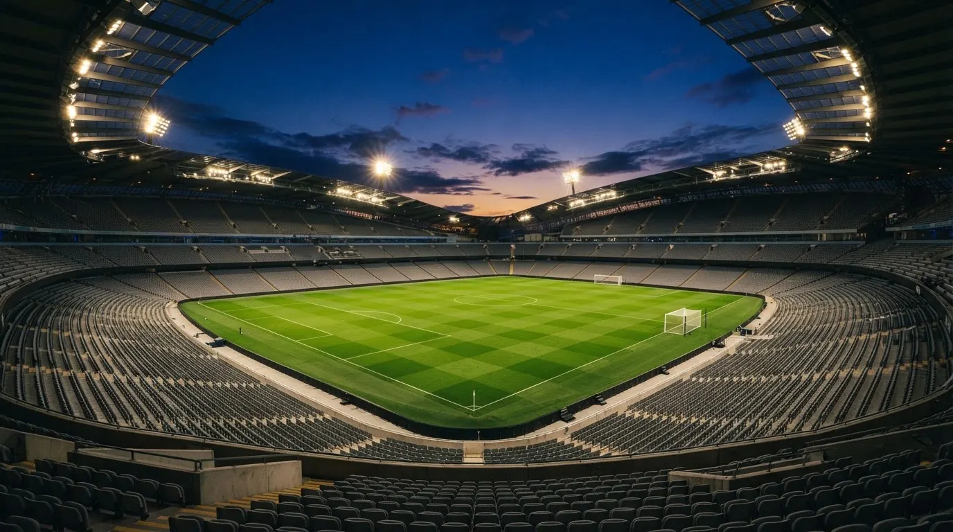 An empty football stadium with floodlight masts at dusk