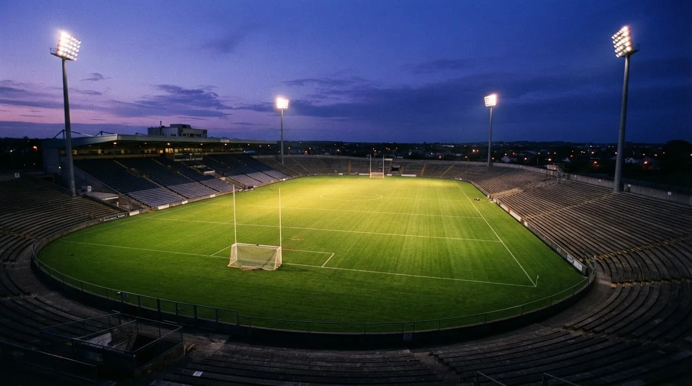 An empty football stadium with floodlight masts at dusk