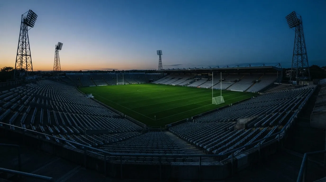 An empty football stadium with floodlight masts at dusk