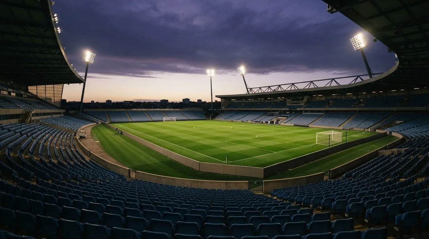 An empty football stadium with floodlight masts at dusk