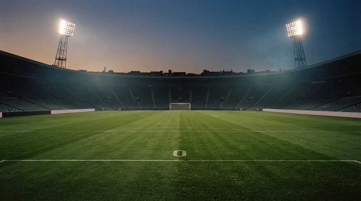 An empty football stadium with floodlight masts at dusk