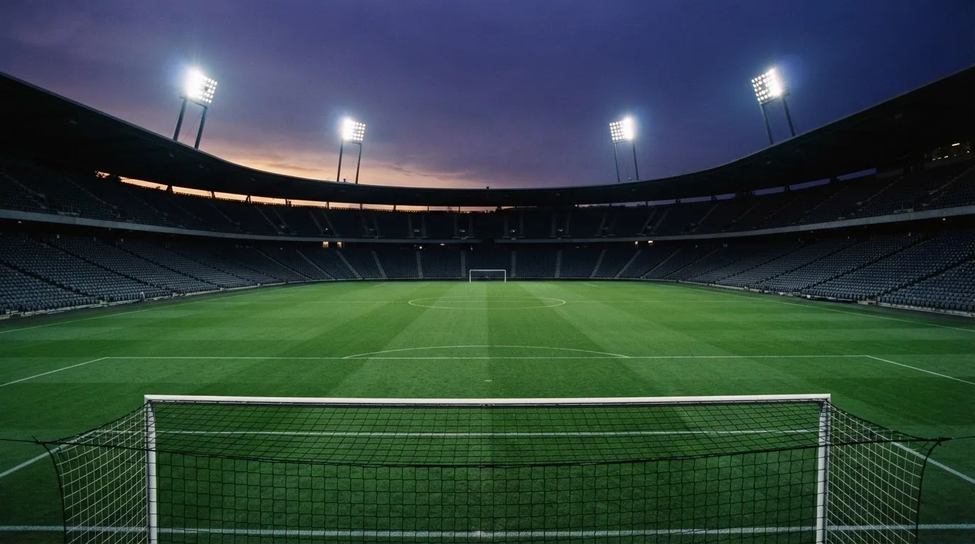 An empty football stadium with floodlight masts at dusk