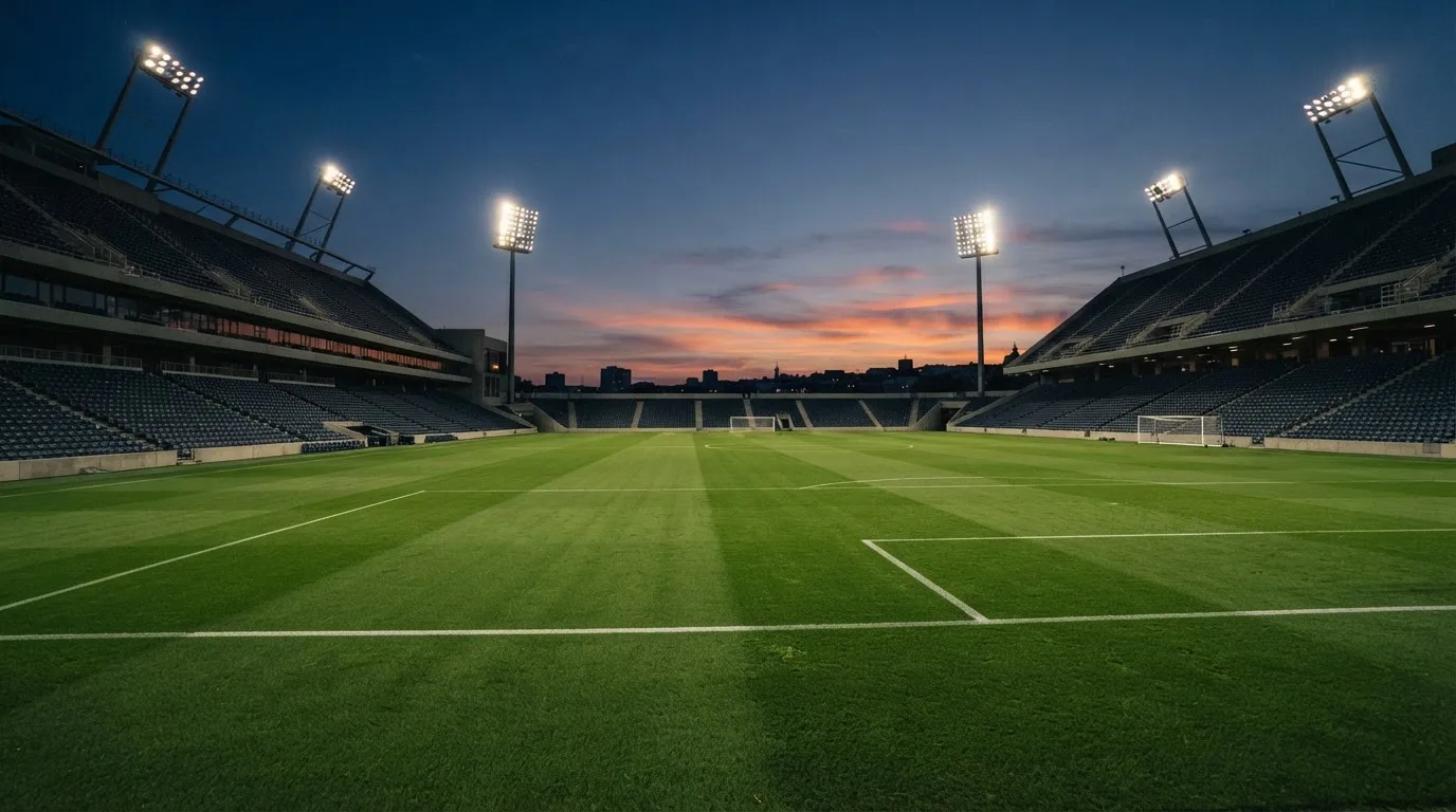 An empty football stadium with floodlight masts at dusk