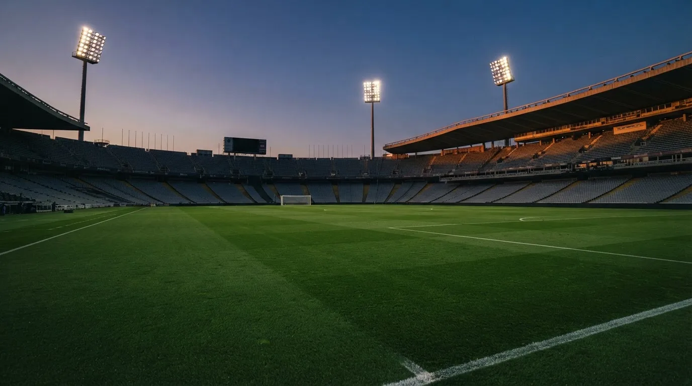 An empty football stadium with floodlight masts at dusk
