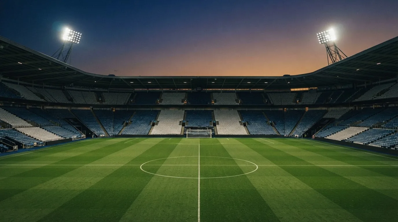 An empty football stadium with floodlight masts at dusk