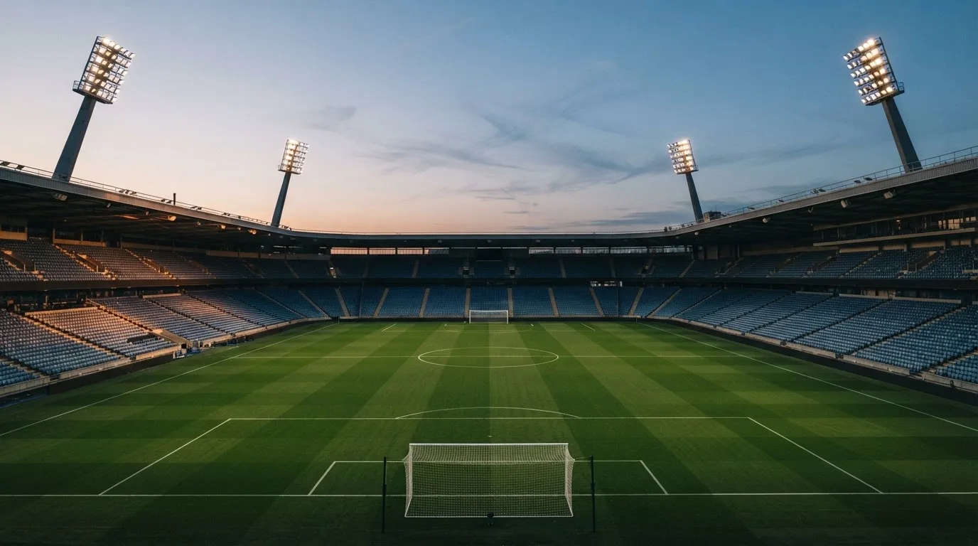 An empty football stadium with floodlight masts at dusk