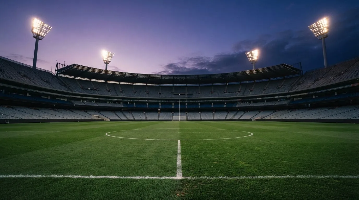 An empty football stadium with floodlight masts at dusk