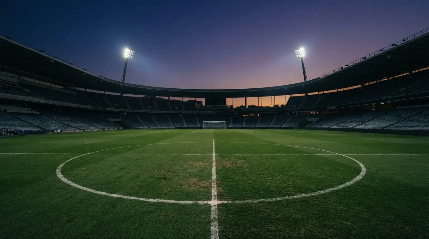 An empty football stadium with floodlight masts at dusk