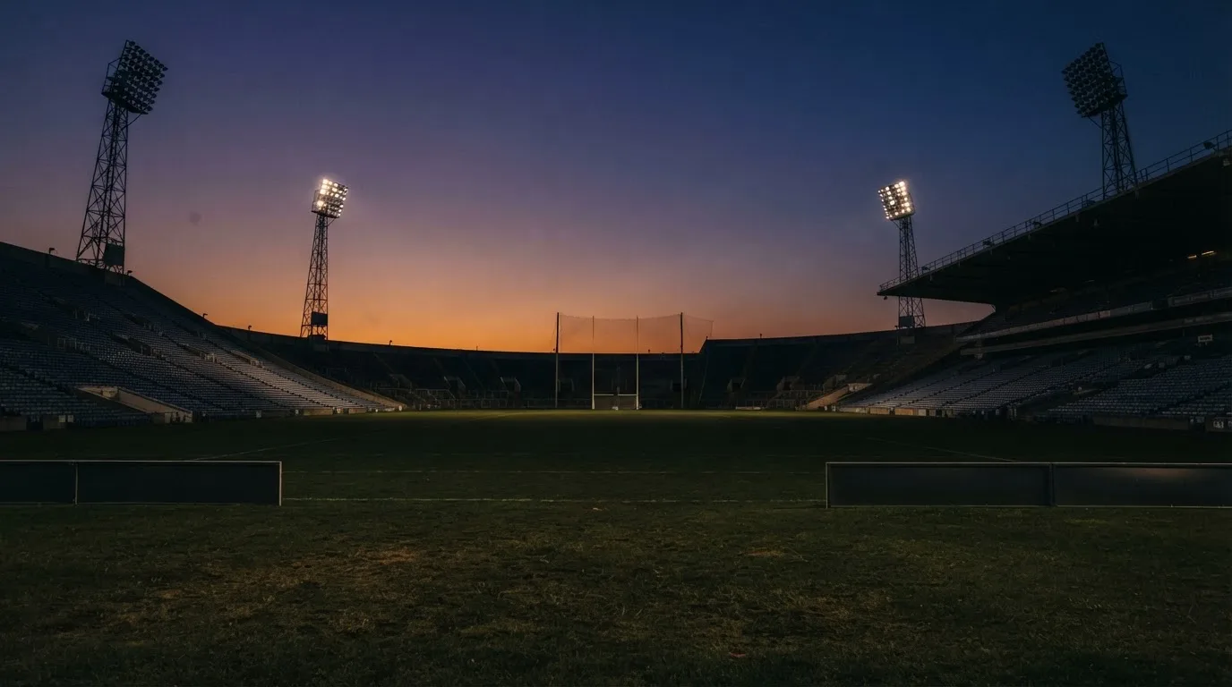 An empty football stadium with floodlight masts at dusk