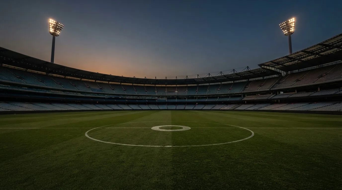 An empty football stadium with floodlight masts at dusk