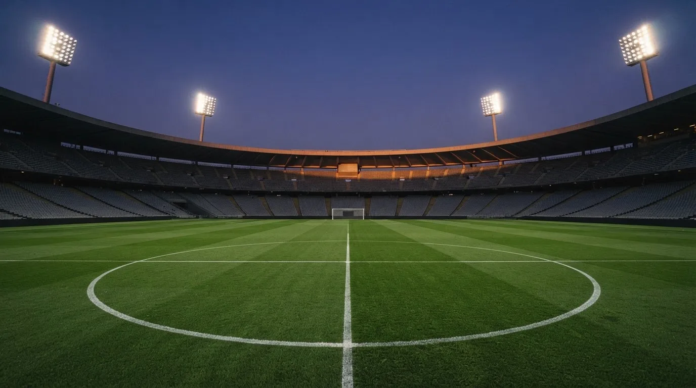 An empty football stadium with floodlight masts at dusk